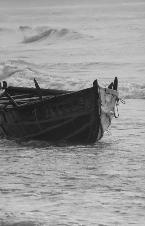 Free Monochrome shot of a traditional wooden fishing boat in calm coastal waters. Stock Photo
