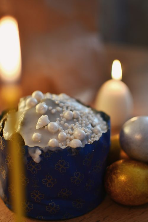 Free Easter cake adorned with pearls surrounded by candles and golden eggs, creating a warm festive atmosphere. Stock Photo
