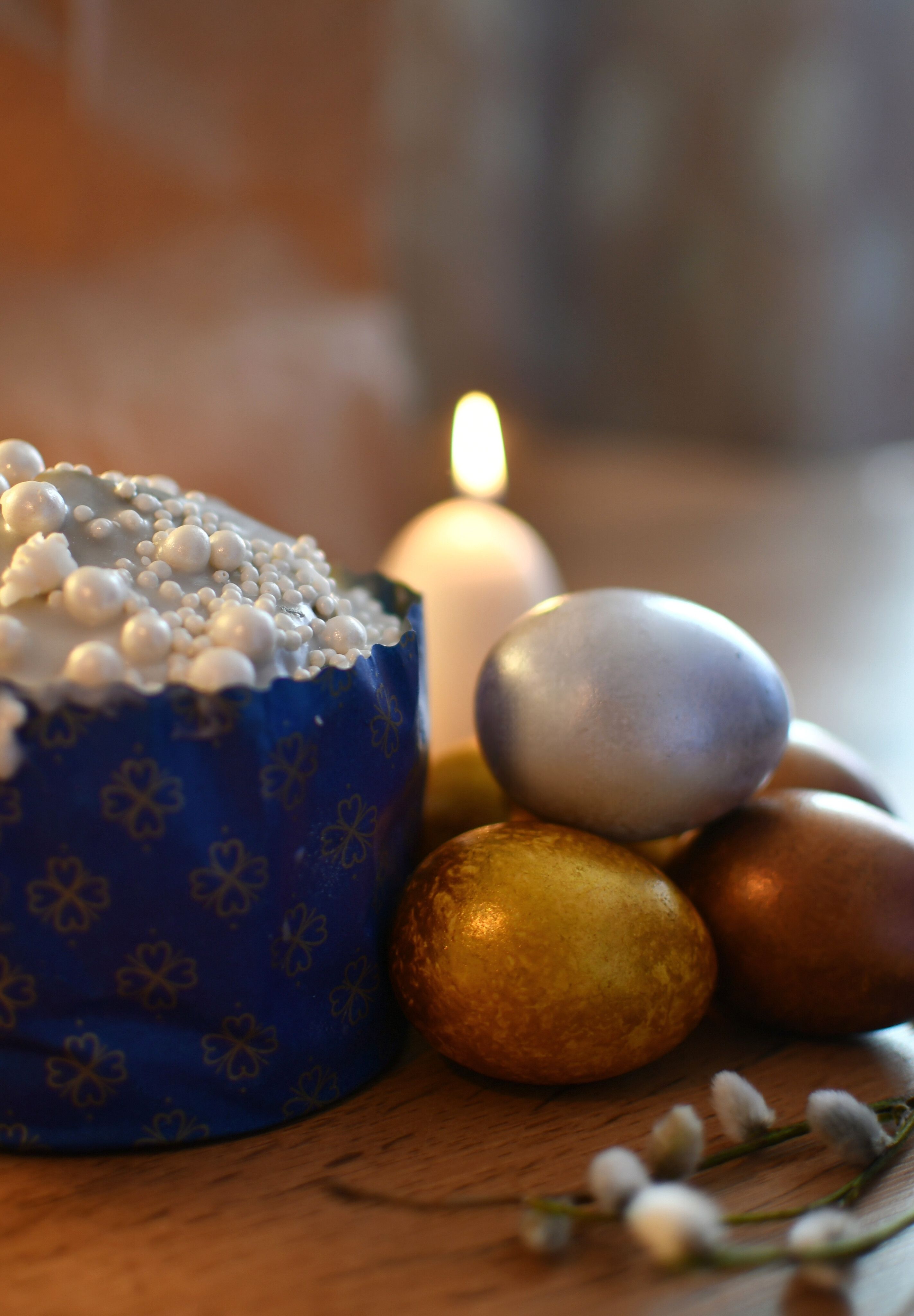 Festive Easter scene with decorated eggs, candle, and cake on a wooden table.