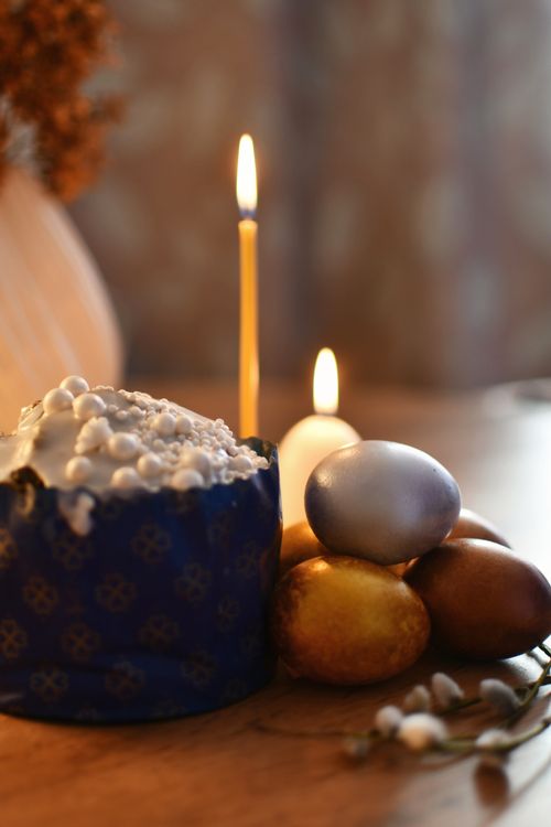 Free Traditional Easter cake and colored eggs with candlelight for a warm holiday ambiance. Stock Photo