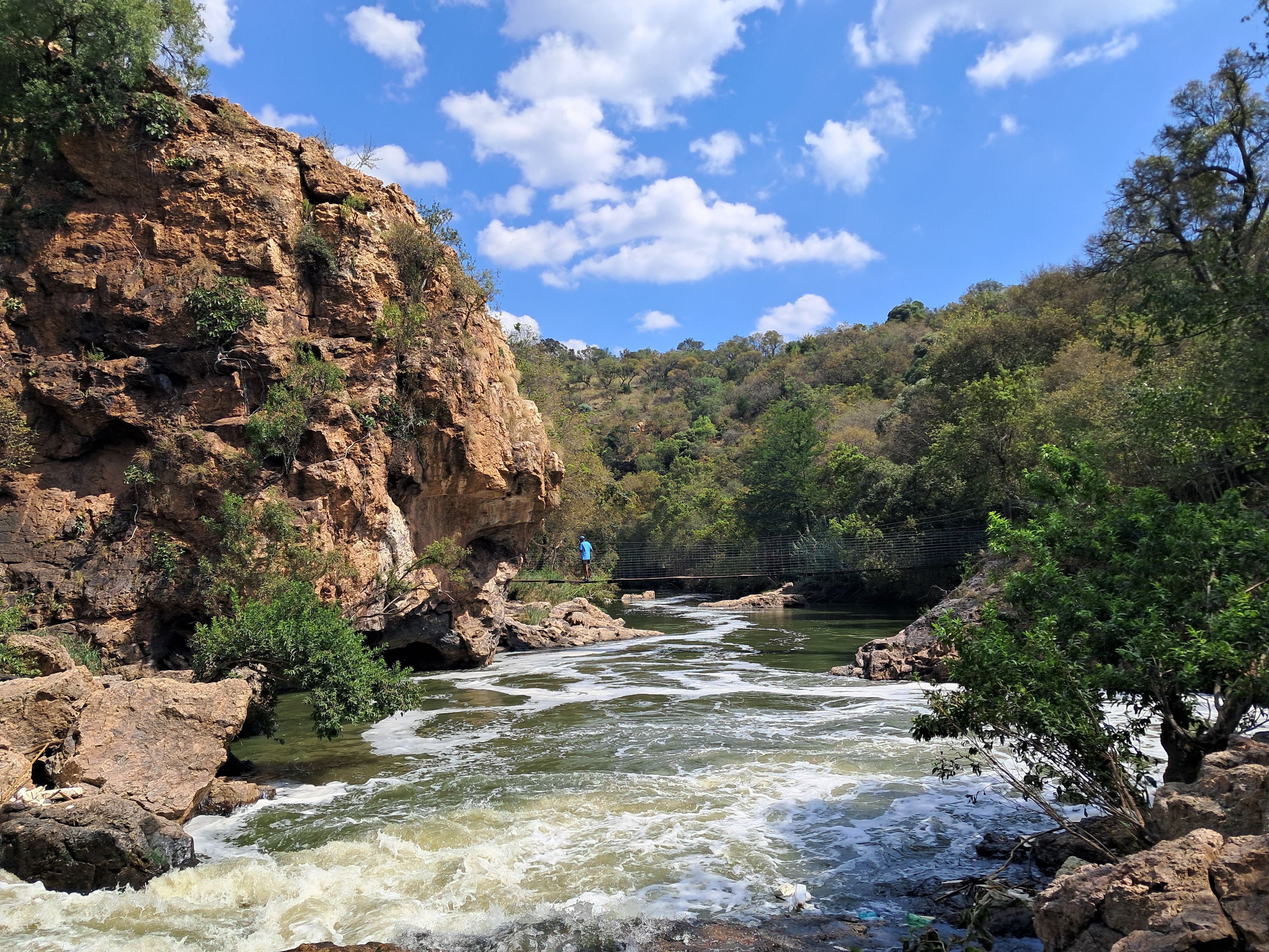 Breathtaking view of a rocky waterfall surrounded by lush greenery in Pretoria, South Africa.