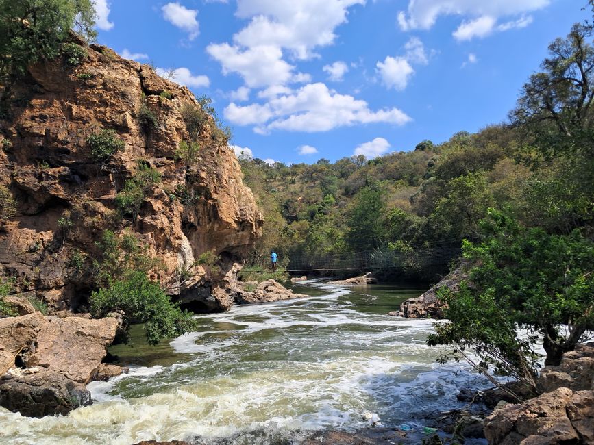 Breathtaking view of a rocky waterfall surrounded by lush greenery in Pretoria, South Africa.