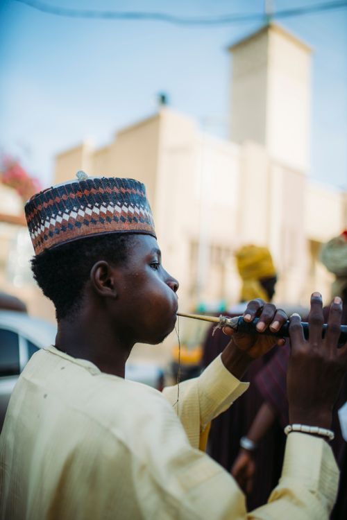 Free A Hausa musician in traditional attire playing the algaita instrument outdoors in Kano, Nigeria. Stock Photo