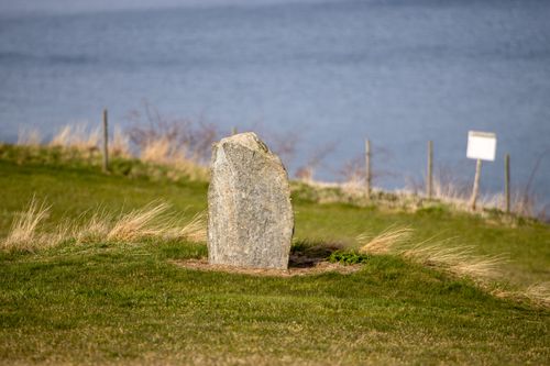 Free Ancient stone standing by the serene lakeside in Gränna, Sweden, amidst green grass. Stock Photo