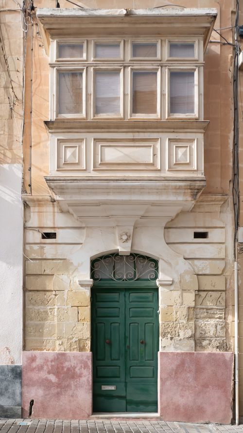 Free Elegant Maltese stone building with traditional wooden balcony and vibrant green door, showcasing classic architecture. Stock Photo