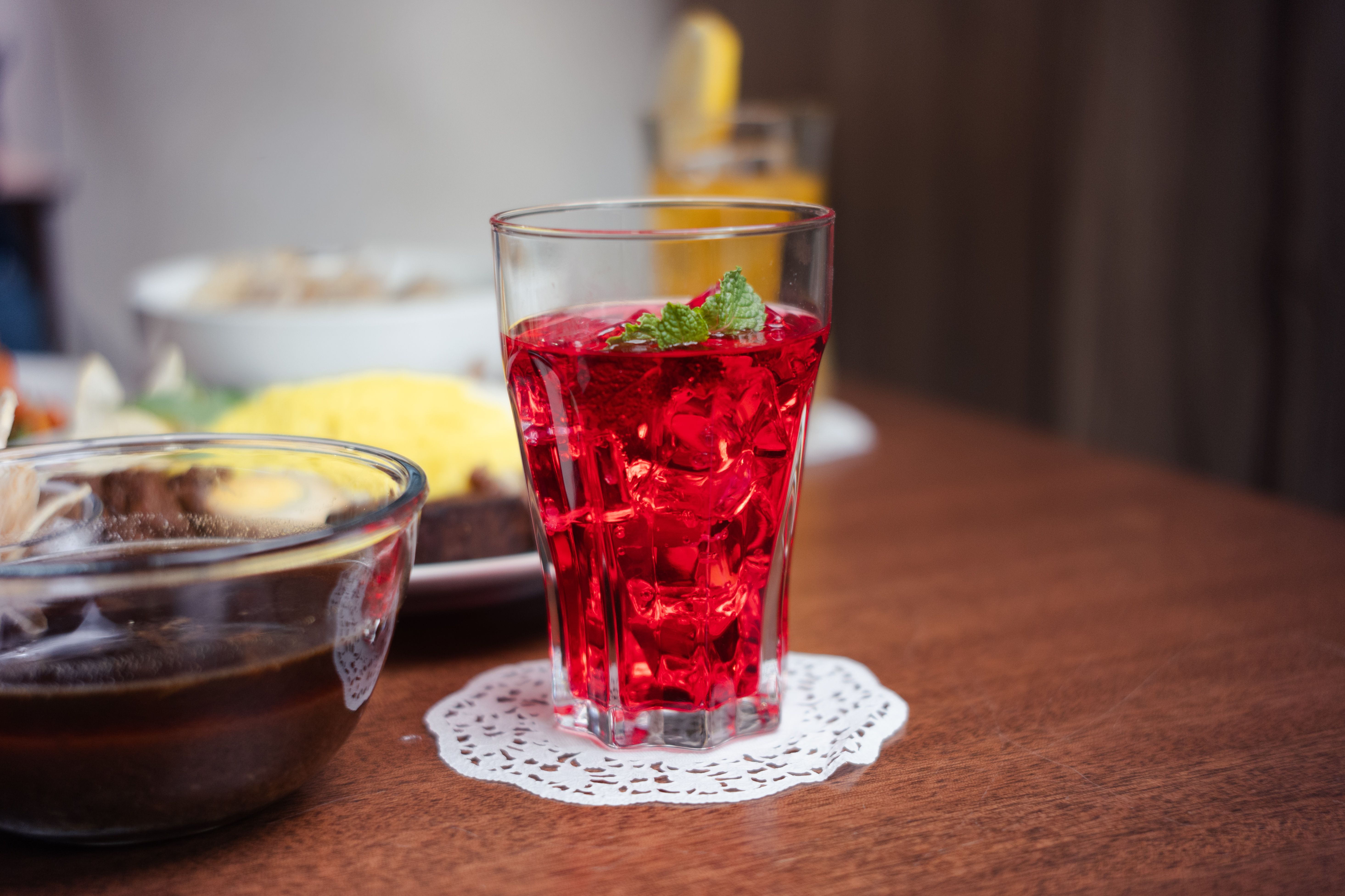 A vibrant red drink with mint garnish on a table, perfect for summer refreshment.