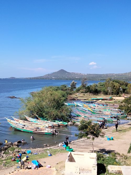 Free Fishermen and boats at the serene shores of Lake Victoria under clear blue skies. Stock Photo