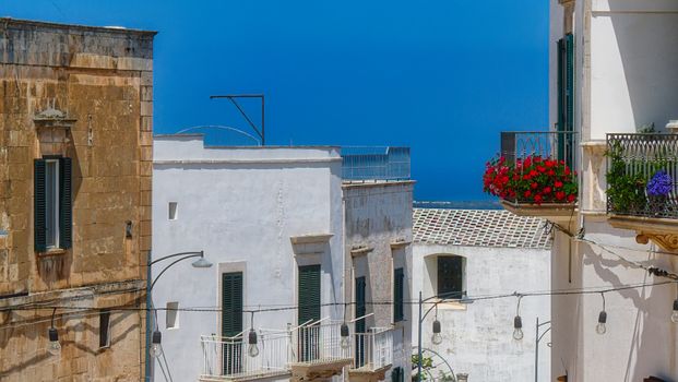 Explore the picturesque whitewashed buildings and vibrant balconies of Ostuni, Italy.