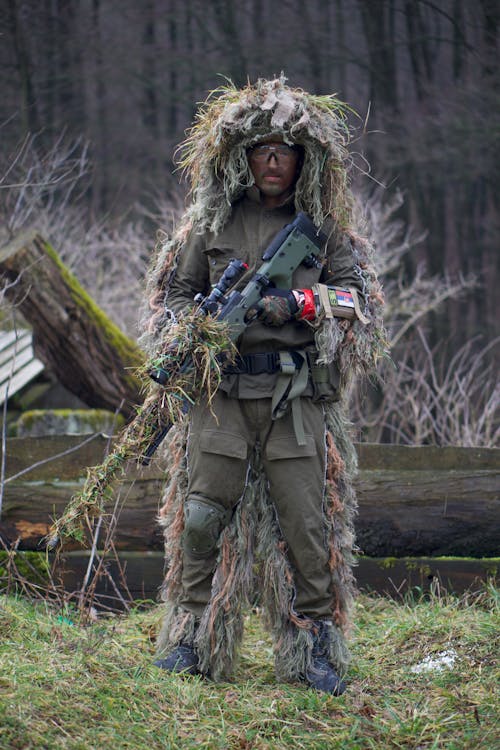 無料 機関銃を持っている緑と茶色のカモフラージュジャケットの人 写真素材