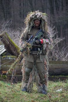 一名身穿迷彩服和吉利服的士兵在森林中手持步枪