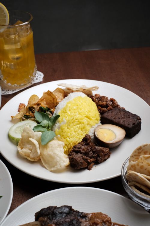Free Traditional nasi tumpeng served with egg, beef, and sides. Perfect for authentic culinary experiences. Stock Photo