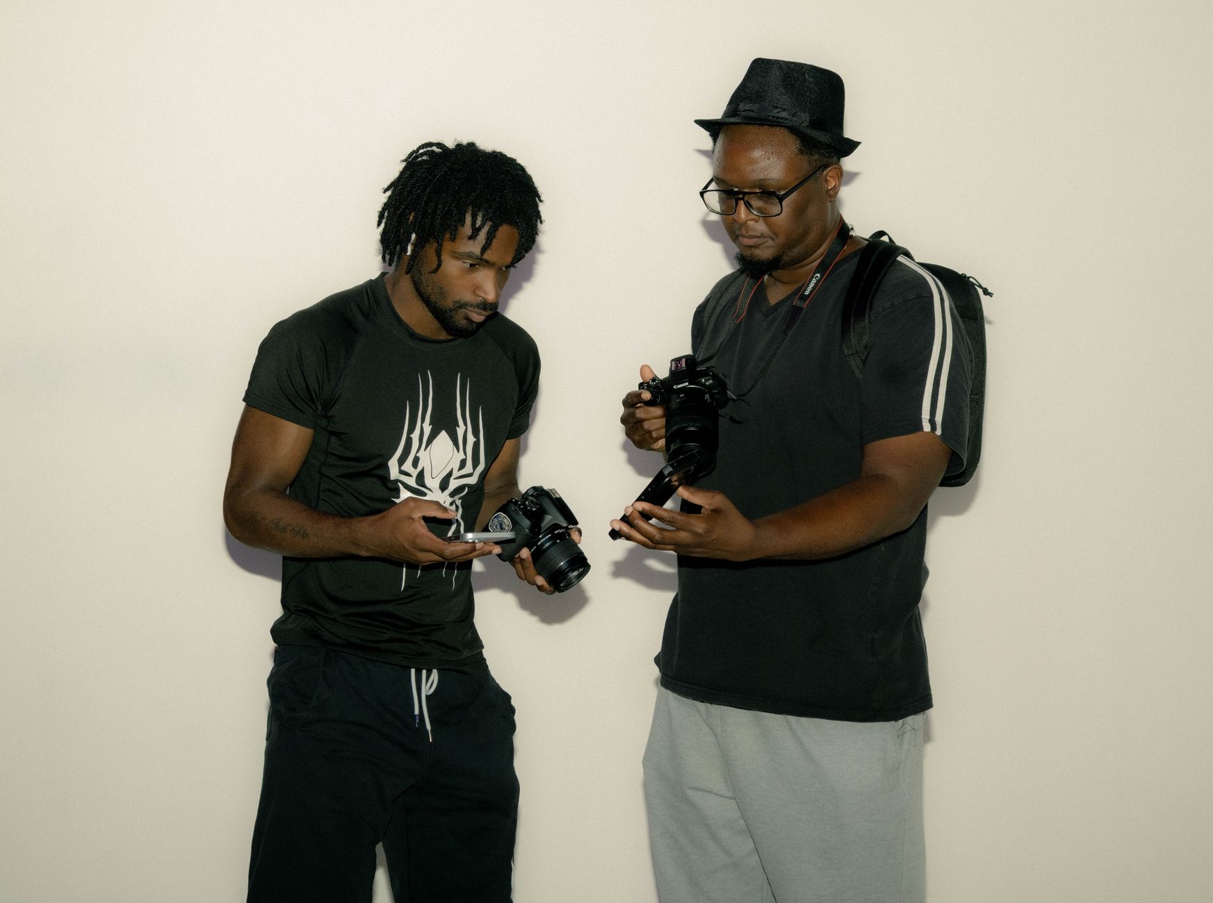 Two photographers indoors discussing and examining cameras passionately, fostering collaboration and learning.