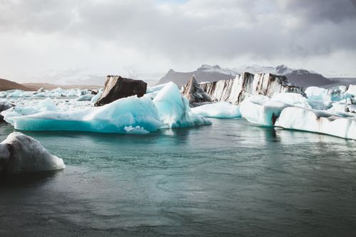 Free Breathtaking view of icebergs floating in a serene Icelandic lagoon with distant mountains. Stock Photo