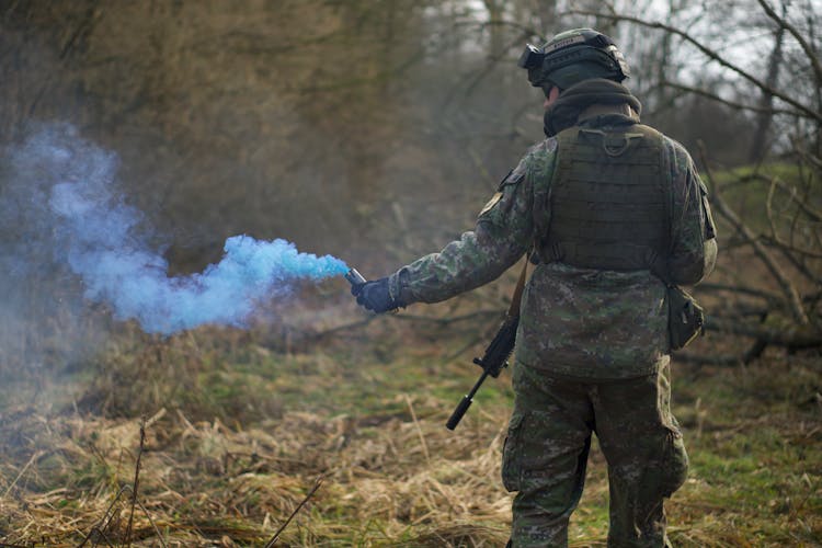 Man In Military Uniform Holding A Signal Smoke