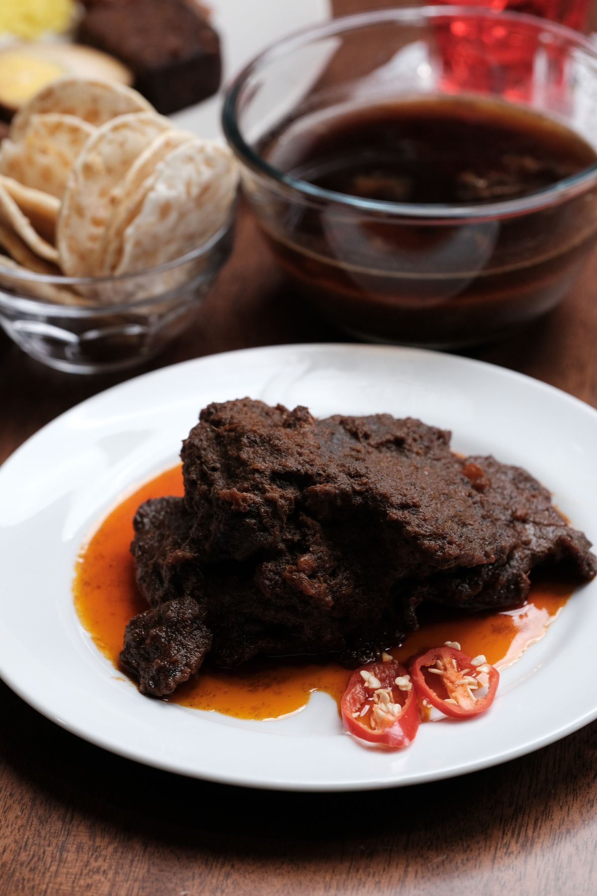 Beef rendang served with spicy red chili slices on a plate