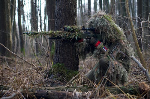 солдат снайпер целится из прицела в лесу