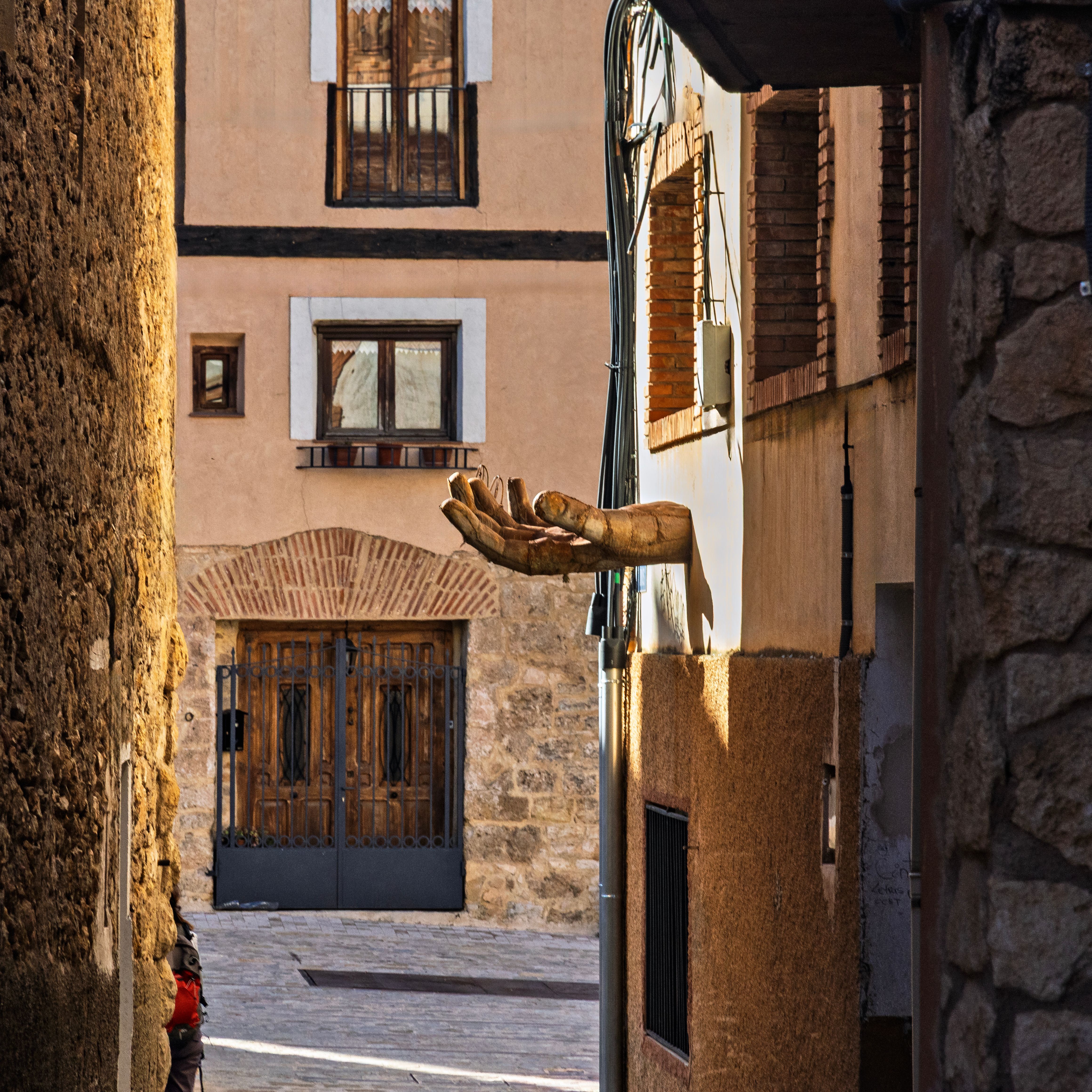 A captivating alley in Castielfabib, Spain featuring an intriguing hand sculpture emerging from a wall.