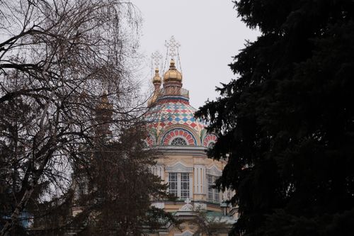 Free View of Zenkov Cathedral through trees in Almaty, Kazakhstan, featuring vibrant domes. Stock Photo