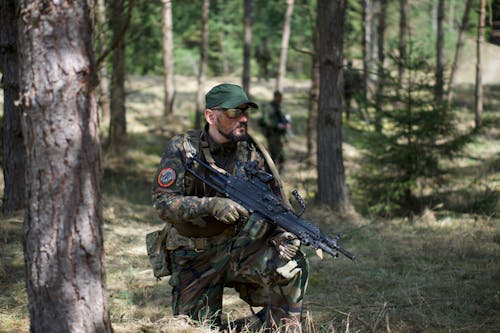 Homem Com Uniforme Do Exército Camuflado Verde E Marrom Segurando Um Rifle