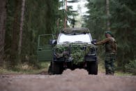 士兵身着迷彩服，在茂密的森林中驾驶装甲车，展示军事准备情况