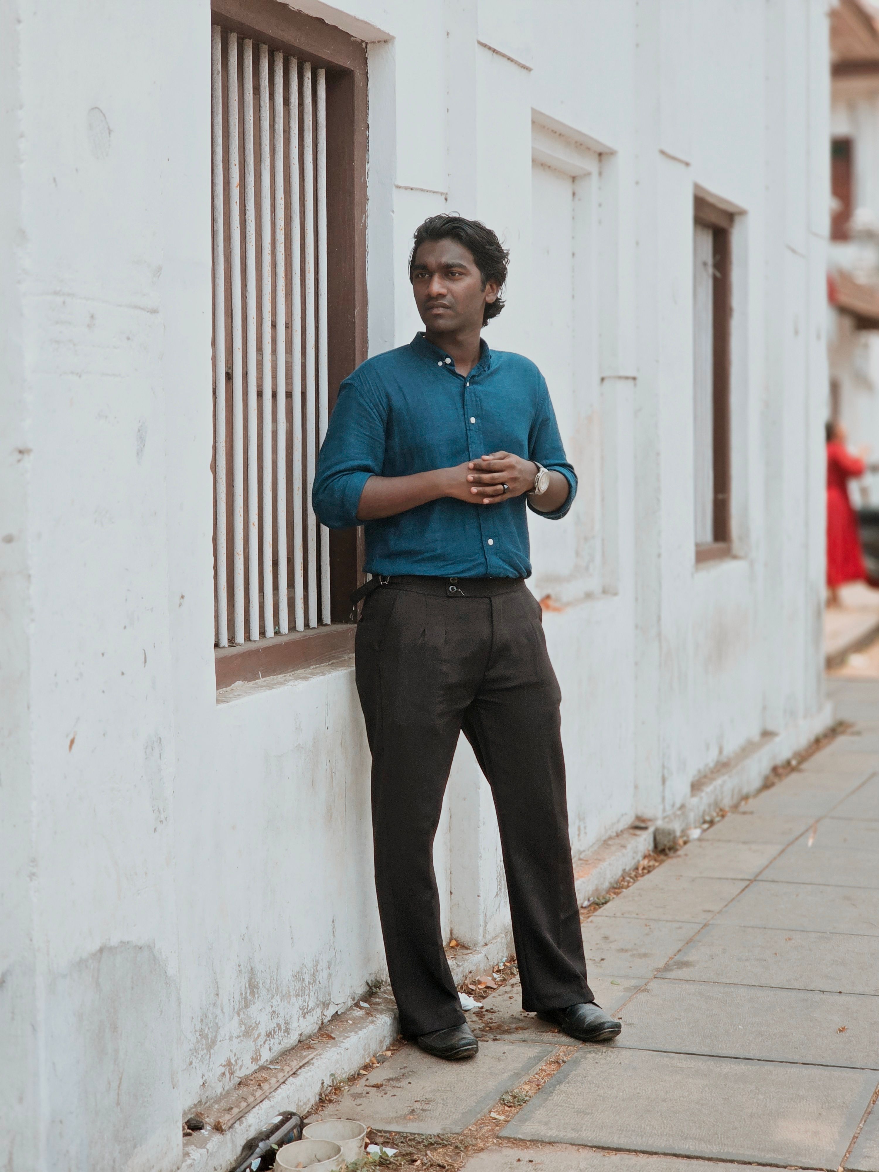 A contemplative man stands by a white wall in an urban setting, adding a serene ambiance.