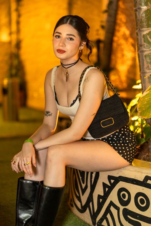 Free Stylish young woman poses outdoors in chic summer attire with vibrant lighting. Stock Photo