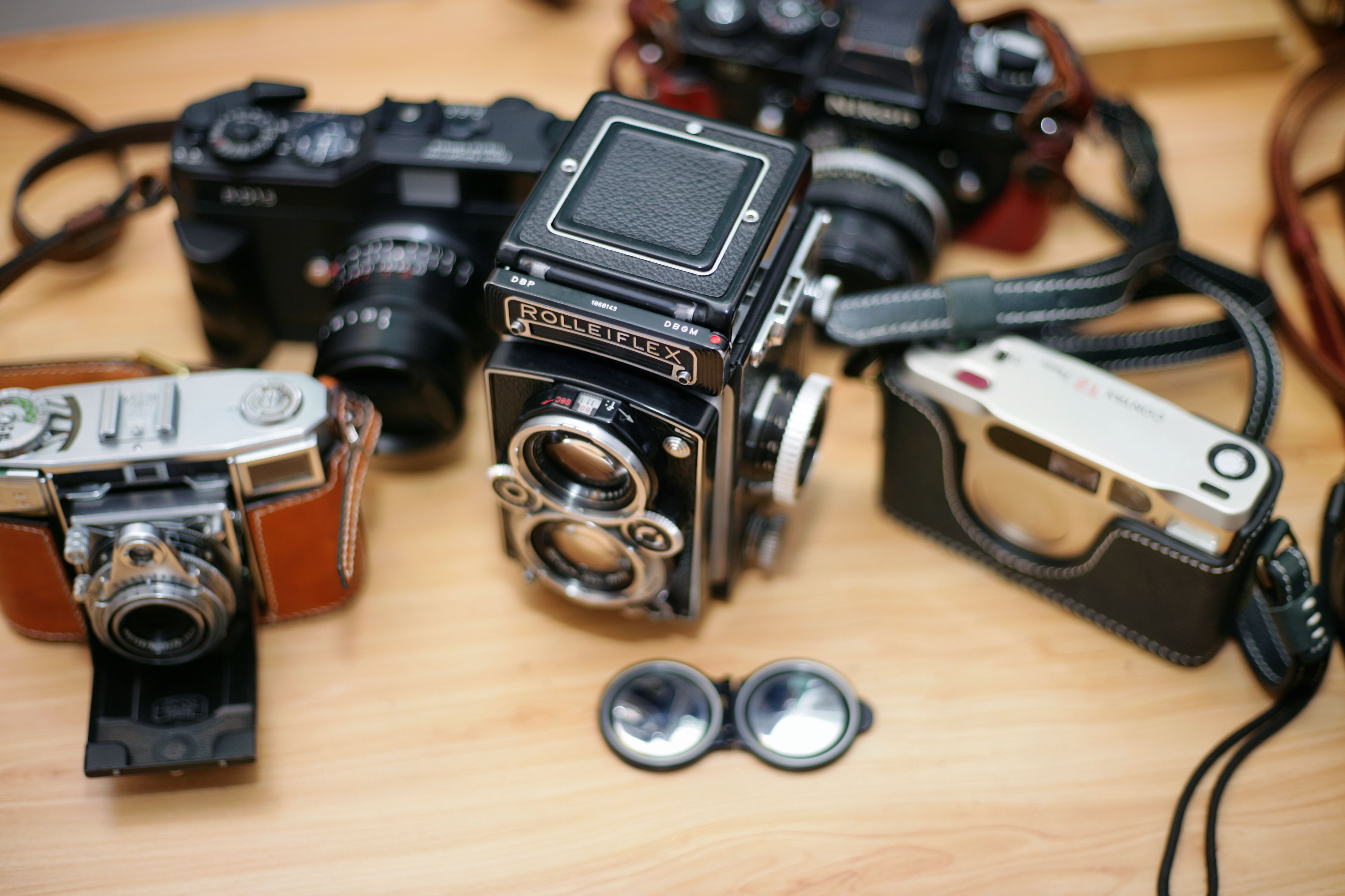 Collection of vintage cameras displayed on a wooden table, showcasing classic photography equipment.