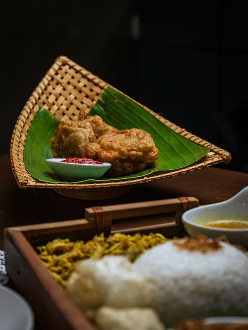 Free Delicious Indonesian dish featuring fried tempeh served on a banana leaf with rice and sambal. Stock Photo