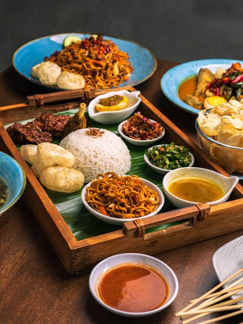 Free An enticing display of traditional Indonesian meals featuring rice, noodles, and side dishes in a bamboo setting. Stock Photo