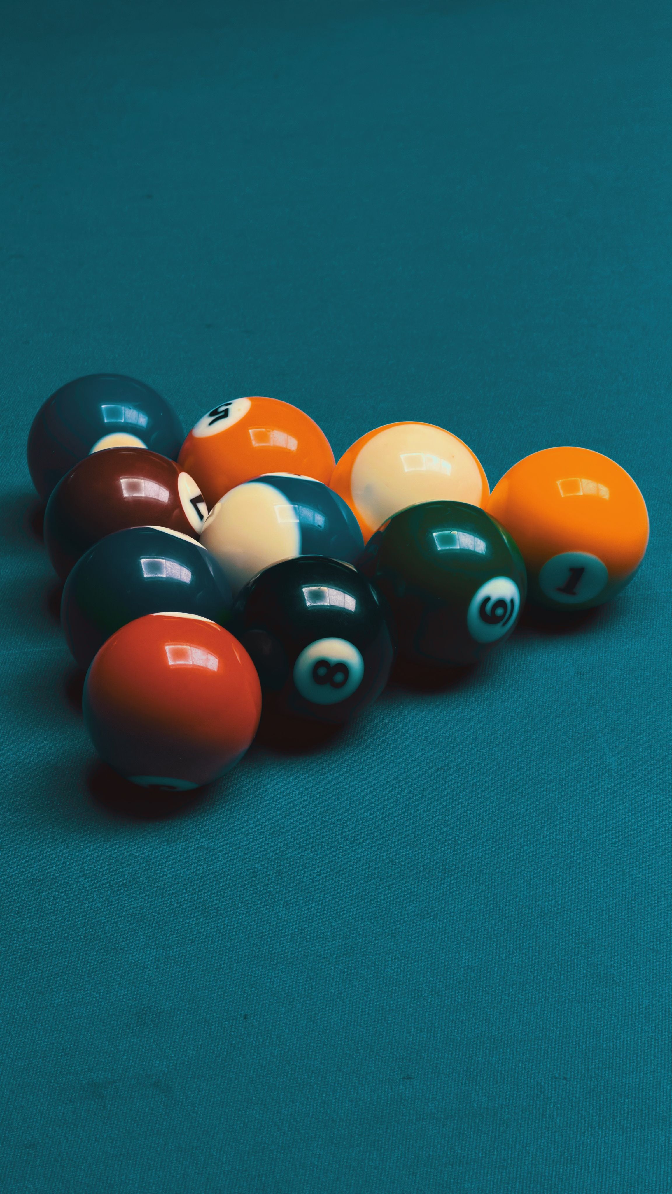 A set of colorful pool balls arranged on a green billiard table cloth ready for a game.