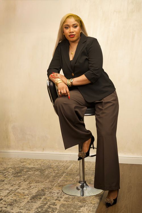 Free Confident businesswoman seated on a stool in formal attire indoors. Professional and stylish setting. Stock Photo