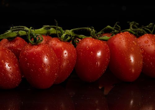 Free Close-up of fresh red tomatoes with water droplets on black background. Stock Photo