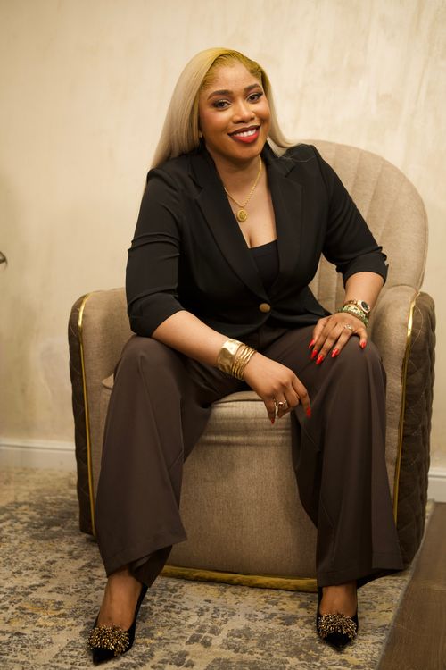 Free Confident woman in stylish black outfit sitting indoors in Abuja, Nigeria. Stock Photo