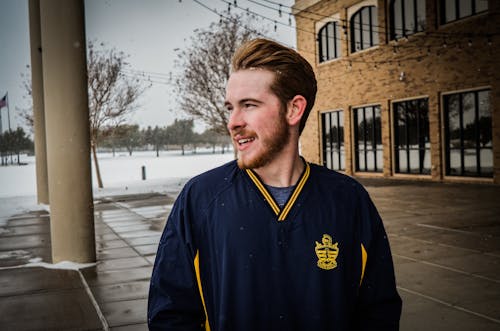 Man in Blue and Yellow Jacket Standing on Sidewalk