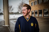 下雪天，一个穿着冬装的年轻人微笑着站在外面的肖像前