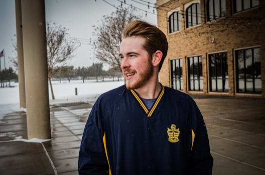 下雪天，一个穿着冬装的年轻人微笑着站在外面的肖像前