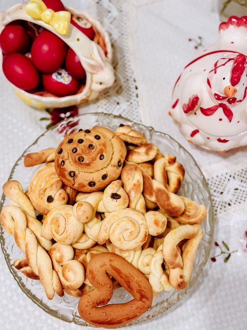 Free A top-down view of traditional Greek Easter cookies and red eggs on a lace tablecloth. Stock Photo