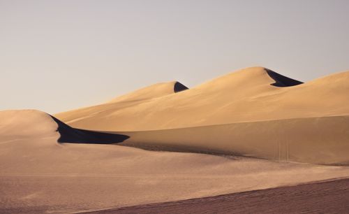 Free Serene landscape of expansive desert sand dunes in warm twilight lighting. Stock Photo