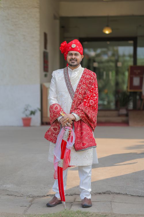 Free Elegant Indian groom posing in red and white traditional attire outdoors, showcasing cultural fashion. Stock Photo