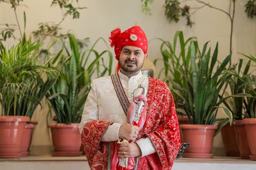 Free A stylish Indian groom dressed in traditional attire poses indoors with lush green plants. Stock Photo