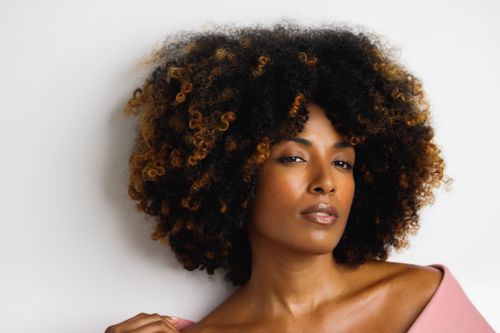 Free Portrait of a woman with voluminous curly hair and a confident look against a white background. Stock Photo