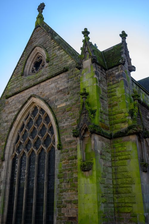 Free Gothic architecture with moss-covered facade of a historic church in England. Stock Photo
