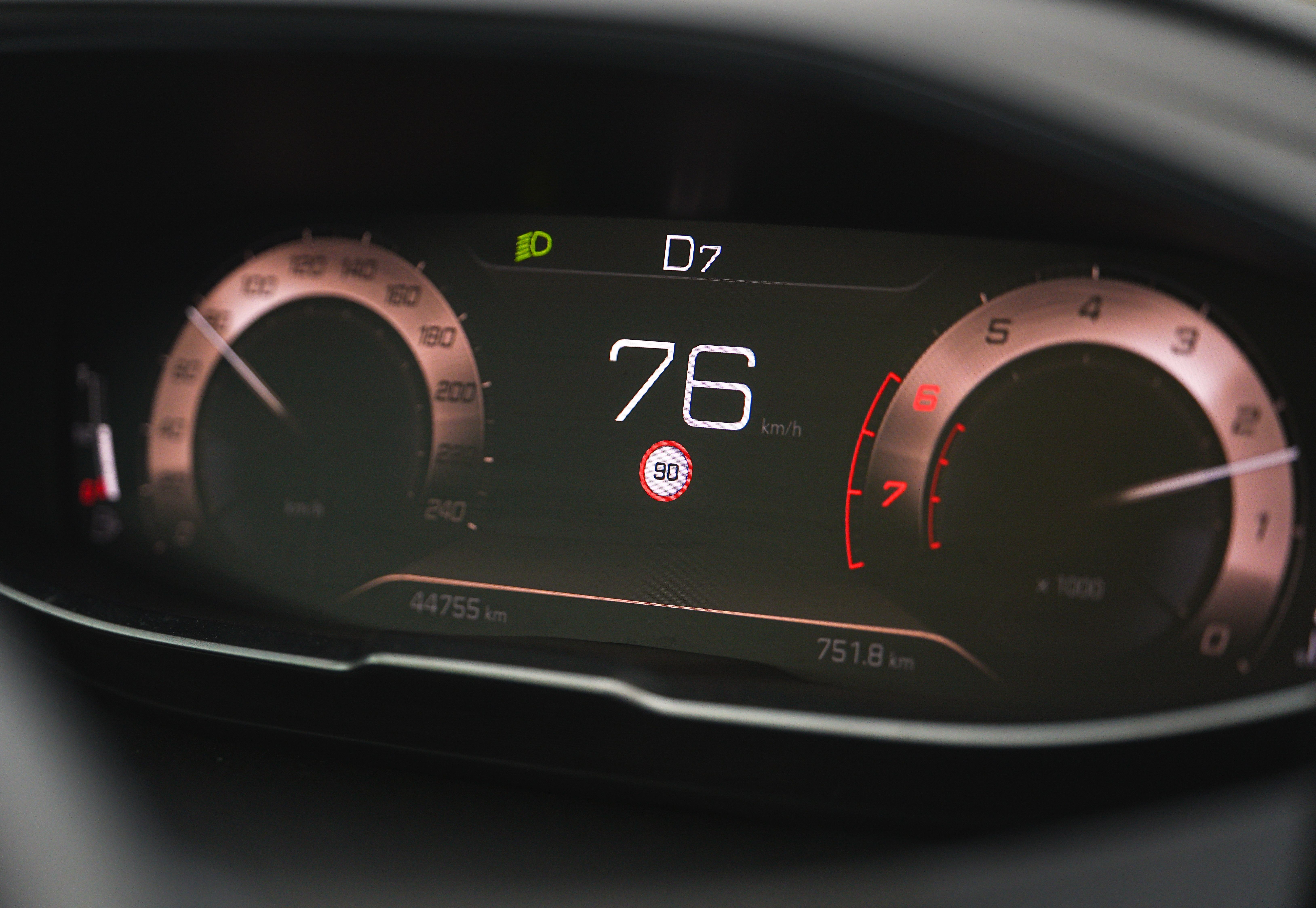 Close-up of a car speedometer display reading 76 km/h with a digital dashboard interface.