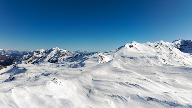 Pristine snow-covered mountains under a clear blue sky in Korutany, Rakousko.
