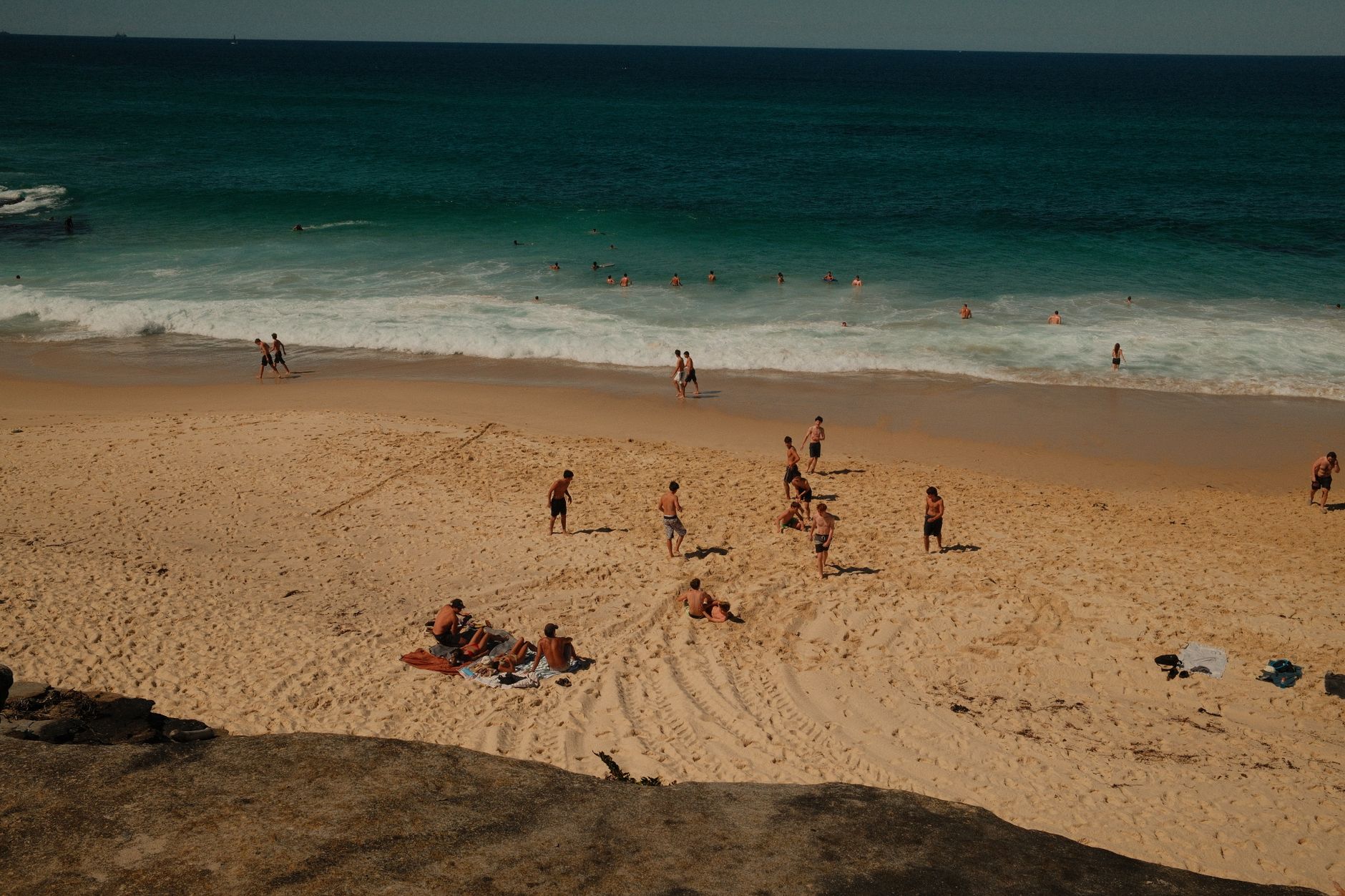 People enjoying a sunny day at the beach in Sydney, Australia with clear blue water and soft sand.