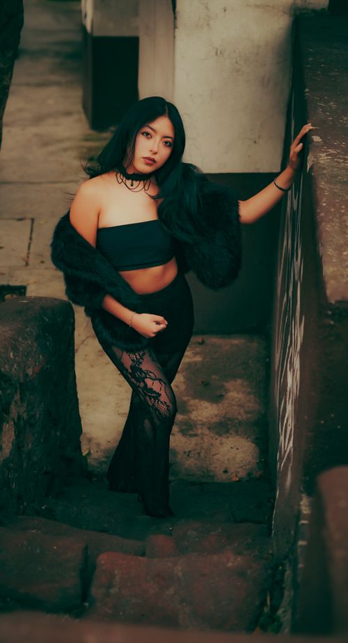 Free Elegant young woman posing on stone staircase in urban setting. Stylish fashion and confident expression. Stock Photo