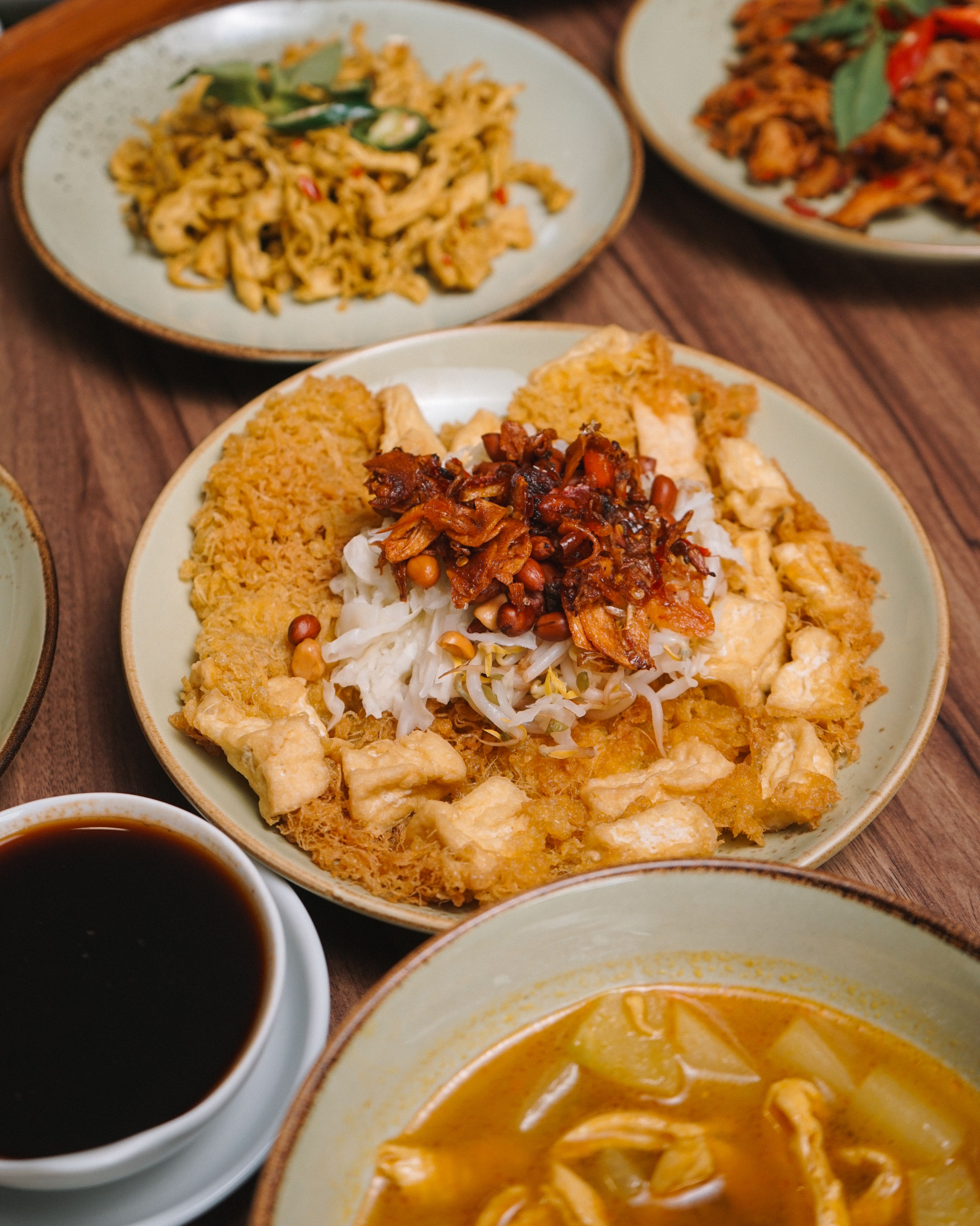 A delightful spread of Indonesian dishes featuring tempeh, tofu, and assorted spices, offering a rich culinary experience.