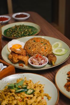 Savor a plate of Nasi Goreng with fried chicken, sambal, and vegetables, an Indonesian classic. - Fotografer Sidoarjo