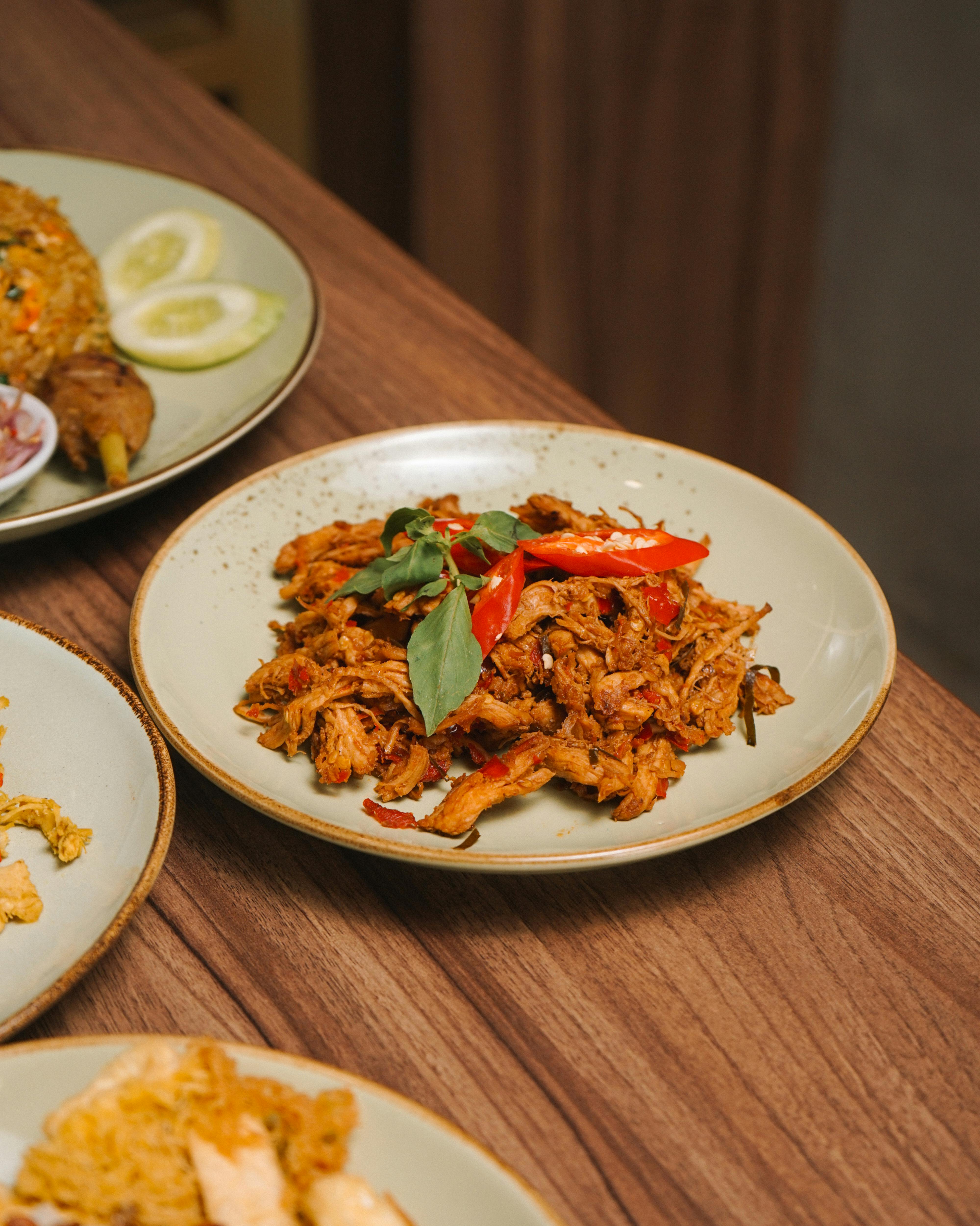 Close-up of a savory shredded chicken dish with red peppers on a dining table.