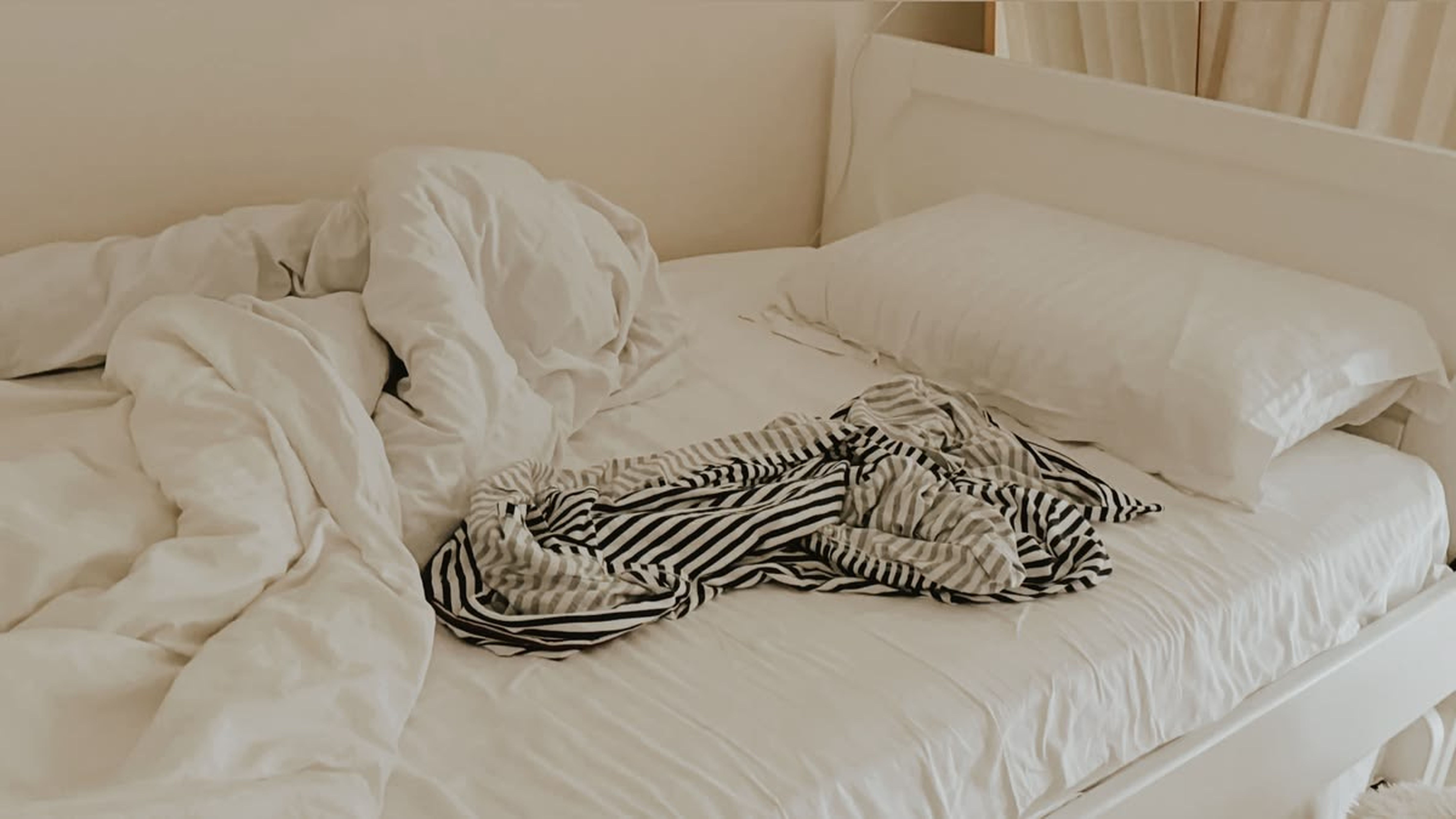 An unmade bed with crumpled sheets — the mattress seams and bed-frame joints are where bed bugs (pepijat) hide
